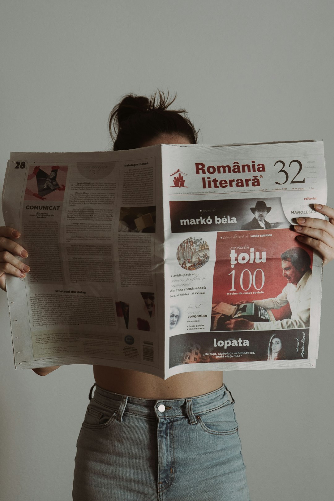 a-woman-is-holding-a-bunch-of-newspapers-sj1jfvxjzwg